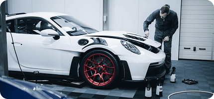Modern bir servis atölyesinde profesyonel detaylandırma işlemi gören üst sınıf spor otomobil